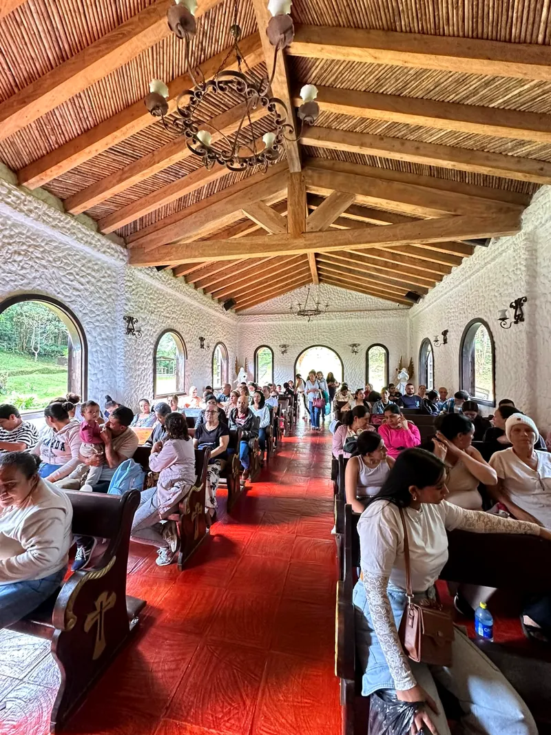 Peregrinos en oración dentro de la capilla de madera y piedra